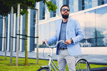 Luxury bearded male in a sunglasses on a bicycle in a downtown.の写真素材