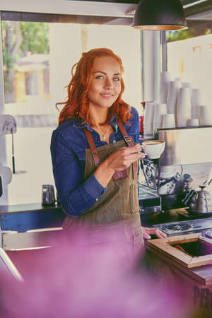 Portrait of redhead female barista in a small coffee shop.の写真素材