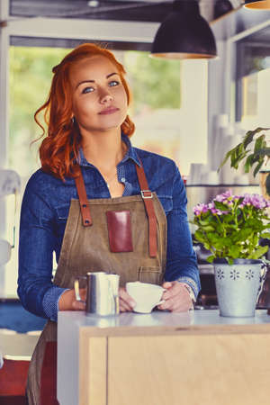 Portrait of redhead female barista in a small coffee shop.の写真素材