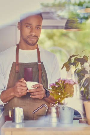 Black bearded coffee seller pouring coffee in a shop.の写真素材
