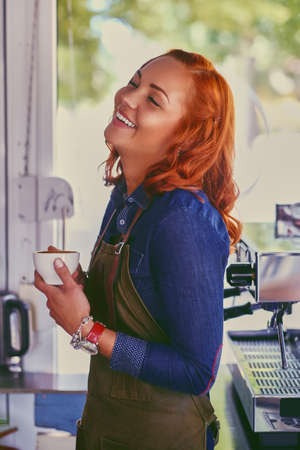 Portrait of redhead female barista in a small coffee shop.の写真素材