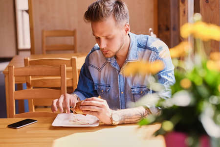 A man in denim jacket eats vegan burger.の写真素材
