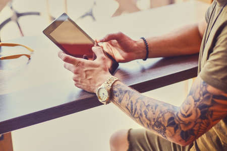 Attractive guy using a tablet PC in a cafe near the window.