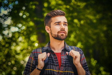Portrait of bearded traveler male dressed in a fleece shirt over wild park background.の写真素材