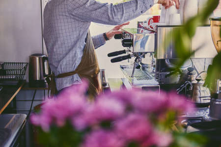 Close up image of a man preparing late in a coffee machine.の写真素材
