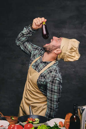 Funny bearded chef cook eats eggplant.の写真素材