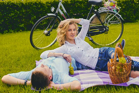 Handsome young male and blond female on a picnic in a summer park.の写真素材
