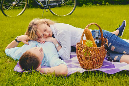Handsome young male and blond female on a picnic in a summer park.の写真素材