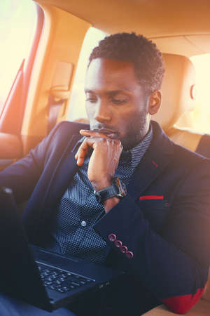 Stylish Black male in a car using a laptop.の写真素材