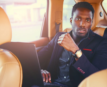 Stylish Black male in a car using a laptop.の写真素材
