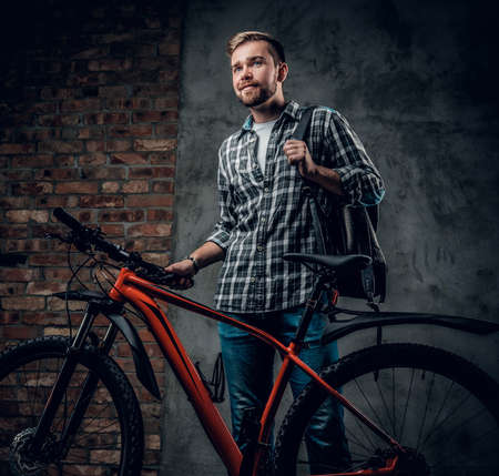 Bearded male dressed in a fleece shirt holds red mountain bicycle.の写真素材