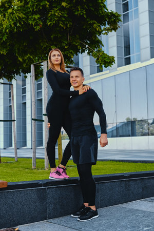 The full body image of athletic fitness couple is posing over modern building background.