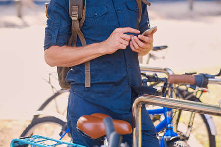 A man with smartphone near bicycles parking area.の写真素材