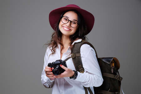 Positive female tourist with photo camera and travel backpack.の写真素材