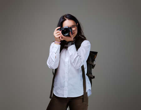 Positive female tourist with photo camera and travel backpack.
