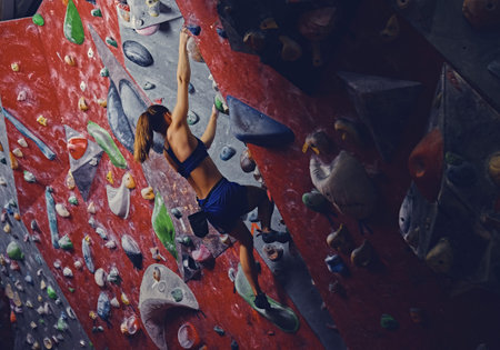 Female climber. Extreme indoor climbing. Side view.の写真素材