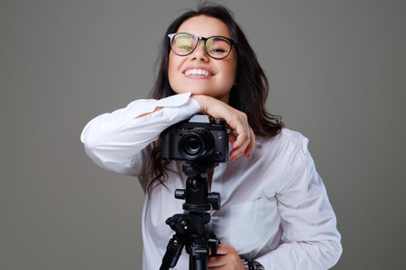 Smiling, positive brunette female in eyeglasses taking pictures with a professional photo camera....