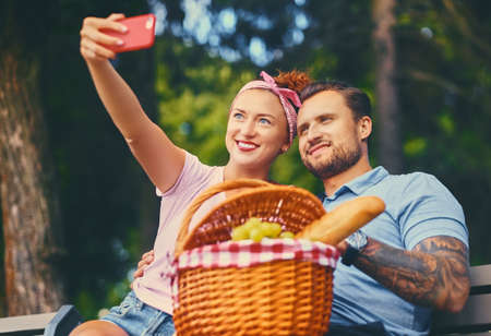 A couple on a picnic  in a city park using smartphone and instant messaging.の写真素材