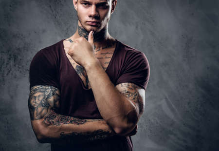 Tattooed male with crossed arms over grey artistic background.の写真素材