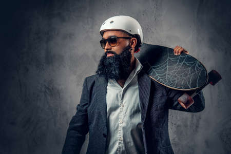 A stylish Arabic male dressed in a grey suit holds long board.の写真素材