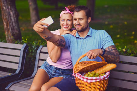 A couple on a picnic  in a city park using smartphone and instant messaging.の写真素材