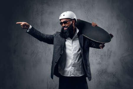 A stylish Arabic male dressed in a grey suit holds long board.の写真素材