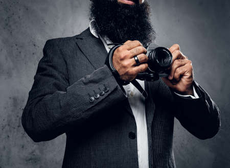 Elegant bearded professional photographer in a suit shooting with a compact DSLR camera.の写真素材