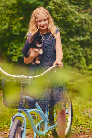 Blond girl on a bicycle holds a Spitz dog.の写真素材