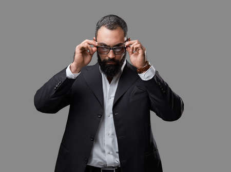 Studio portrait of bearded male dressed in a suit and sunglasses over grey background.の写真素材