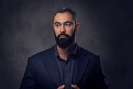 Studio portrait of serious, bearded male dressed in a suit.