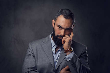 Studio portrait of serious, bearded male dressed in a suit.