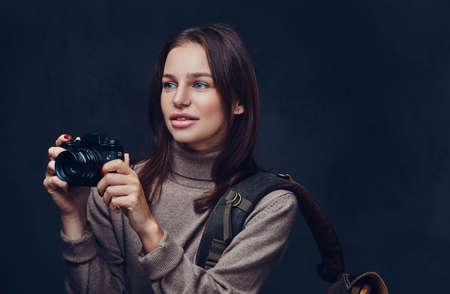 A woman with backpack holds compact photo camera.の写真素材