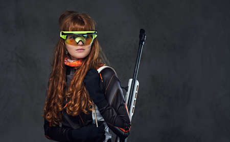 Redhead Biatlon female sportsmen in eyeglasses holds competitive gun.の写真素材