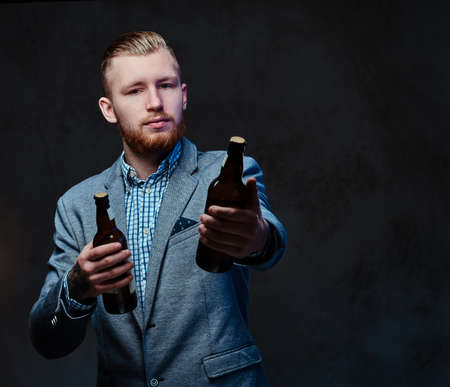 A man dressed in a suit holds a bottle with craft beer.の写真素材