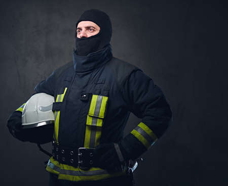 Brave firefighter in a uniform holds safety helmet.