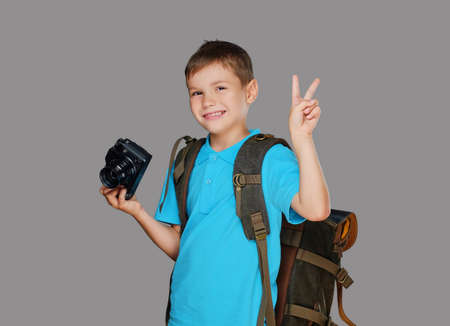 Preschooler boy taking pictures with a professional photo camera. Isolated on grey background.の写真素材