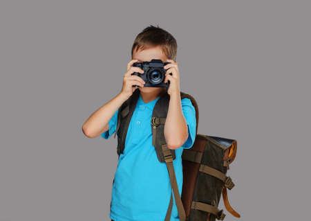 Preschooler boy taking pictures with a professional photo camera. Isolated on grey background.の写真素材