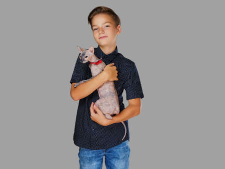 Emotional little boy holds a cat. Isolated on grey background.の写真素材