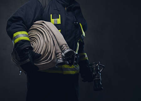 Studio portrait of a firefighter in uniform holds fire hose.の写真素材