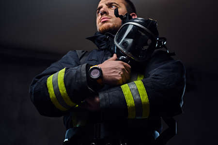Studio portrait of a male dressed in a firefighter uniform holds an oxygen mask.の写真素材