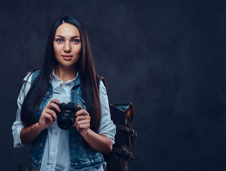 A woman with backpack holds compact photo camera.の写真素材