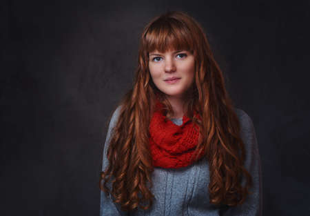 Studio portrait of redhead female over grey background.