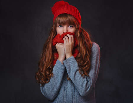 Studio portrait of redhead female over grey background.