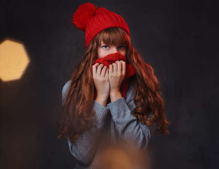 Studio portrait of redhead female over grey background.
