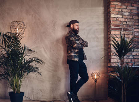 Bearded man posing over the wall in a room with loft interior.の写真素材