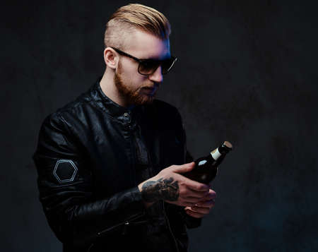 Bearded male holds a bottle with craft beer.の写真素材