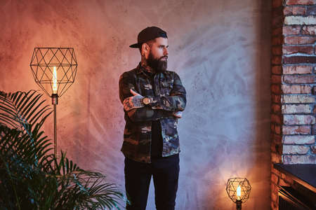 Bearded man posing over the wall in a room with loft interior.