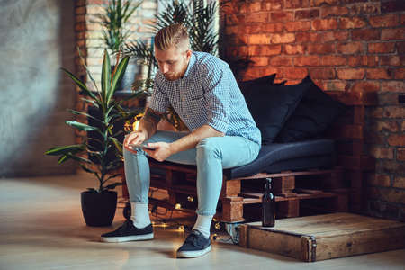 The full body image of blond stylish male using a tablet PC.