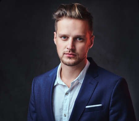 A man dressed in a suit over dark grey background.