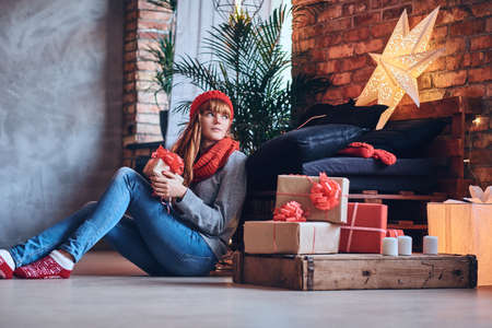 A woman holds a Christmas gift in a living room with loft interiの写真素材
